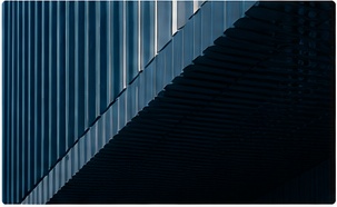 Ribbed blue metal building skin split by a diagonal shadow